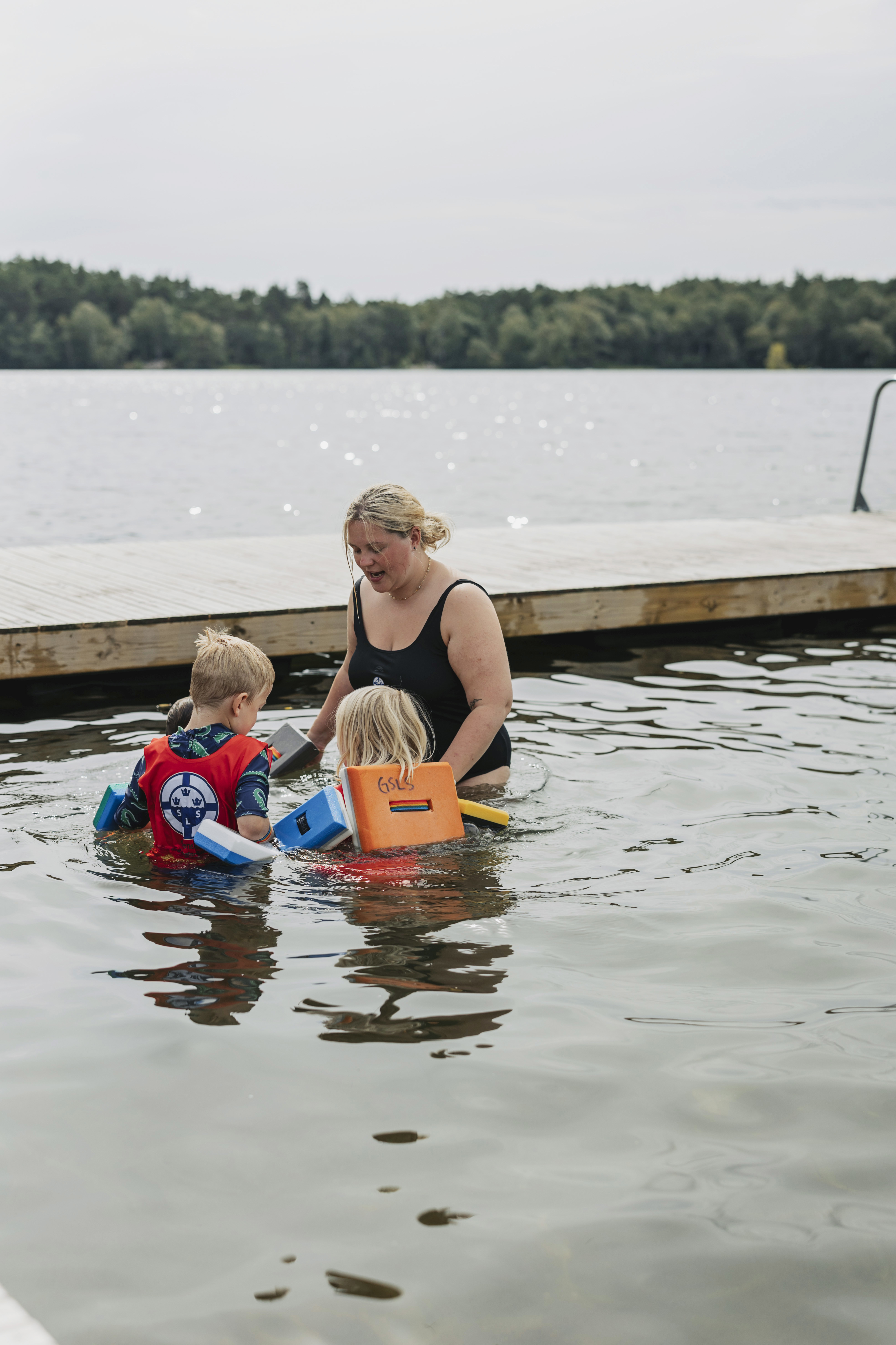 En simskolelärare håller yngre barn i handen och bildar en ring för att träna vattensäkerhet i simskolan vid Sisjön i Mölndal. 
