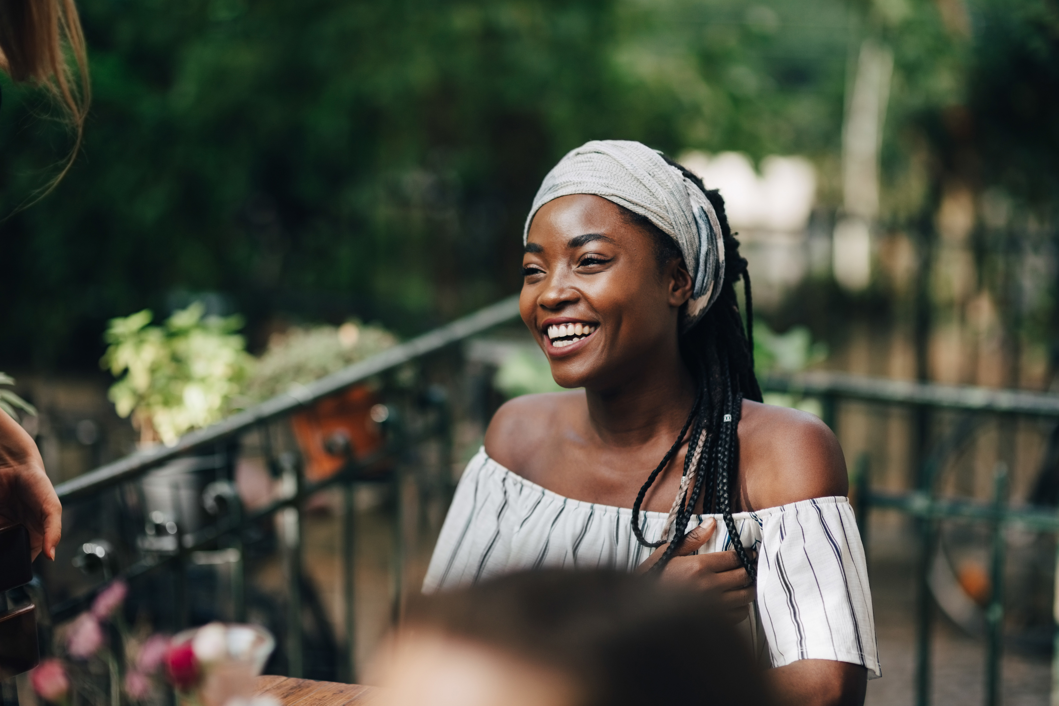 Ung kvinna njuter leende på en balkong tillsammans med vänner. 