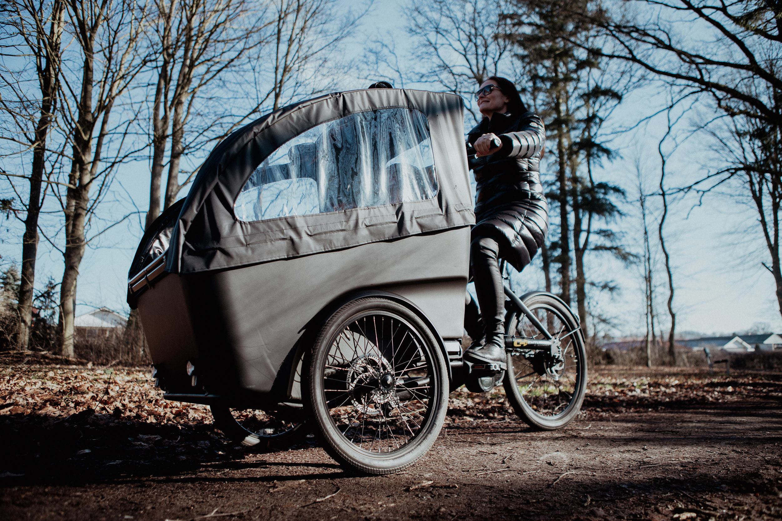 En kvinna kör en lastcykel i ett höstligt landskap. 
