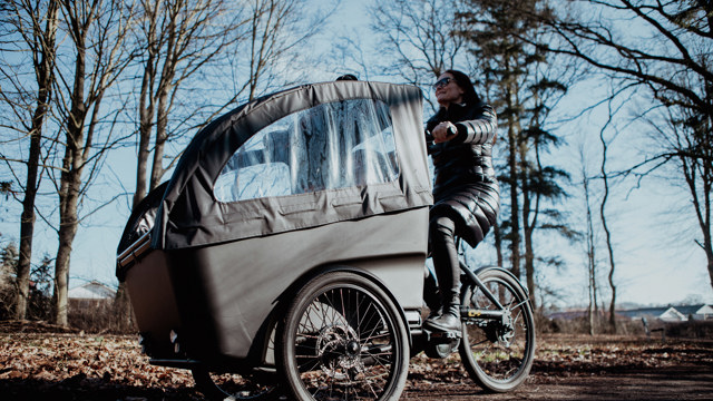 En kvinna kör en lastcykel i ett höstligt landskap. 